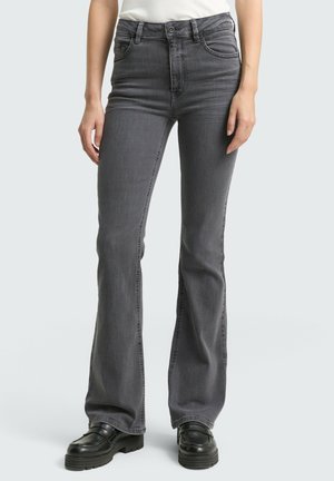 Jeans gris évasés en denim avec une taille haute, dotés de poches avant et d'un léger dégradé. Associés à des chaussures à plateforme noires.