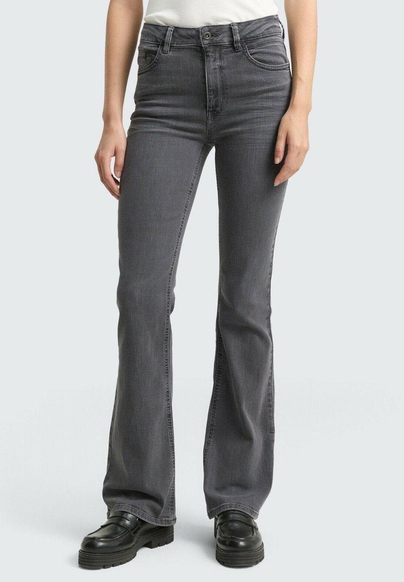 Jeans gris évasés en denim avec une taille haute, dotés de poches avant et d'un léger dégradé. Associés à des chaussures à plateforme noires.