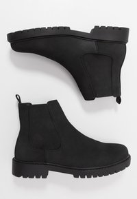 Bottes Chelsea noires en daim lisse avec des panneaux latéraux élastiques. Semelle en caoutchouc épaisse avec bords dentelés et languette à l'arrière pour faciliter l'enfilage.