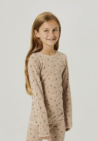 Maglietta a maniche lunghe di un delicato rosa con motivo floreale e rifiniture in pizzo, abbinata a pantaloni coordinati. Tessuto morbido con una vestibilità comoda.