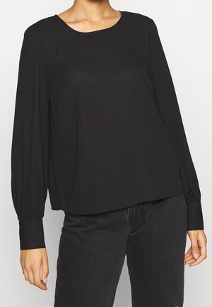 Blouse noire à manches longues avec un col rond et un léger éclat, présentant des détails froncés aux épaules et aux poignets. Texture de tissu lisse.