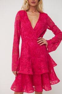 Rochie din dantelă fuchsia cu decolteu adânc în V, mâneci lungi și tiv cu volane suprapuse. Model floral cu textură transparentă care îmbunătățește designul.