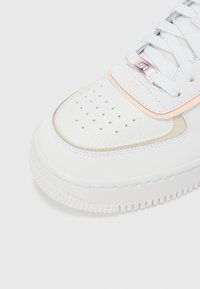 Baskets blanches avec un dessus en cuir texturé, une zone de ventilation au niveau des orteils et des accents pastel. Comprend une semelle en caoutchouc pour une meilleure adhérence et durabilité.