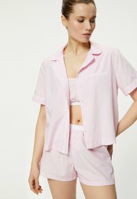 Conjunto de pijama corto a rayas rosa y blanco que incluye una camiseta de botones de manga corta y pantalones cortos a juego con cinturilla elástica.