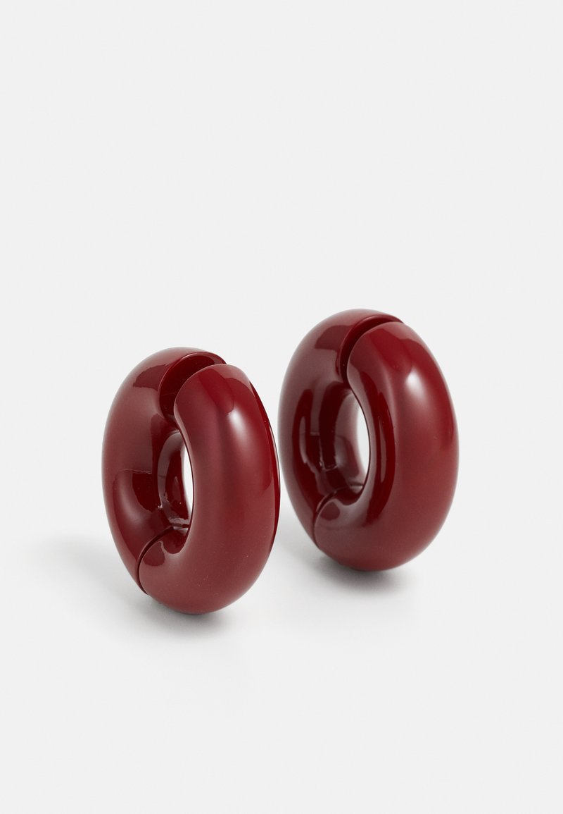 Küpsetatud punased läikivad vaigust rõngas kõrvarõngad, millel on sile, ümar disain ja keskel lõige. Omab sujuvat, mahukat siluetti.