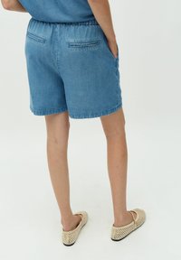 Jeans kratke hlače v svetlo modri barvi z elastičnim pasom, stranskimi žepi in dvojnimi zadnjimi žepi. Gladka tekstura, dolžina do kolen.