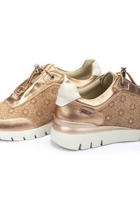 Baskets couleur or rose avec motif floral, finition métallique, accents blancs et semelle robuste. Comprend des lacets et des détails décoratifs.