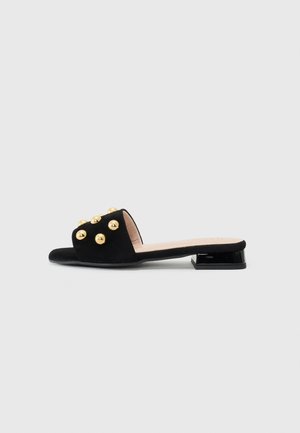 Pantof cu slip-on din suede negru, cu tocul scăzut și dreptunghiular, decorat cu ținte rotunde de culoare aurie pe partea superioară și căptușeală interioară netedă.