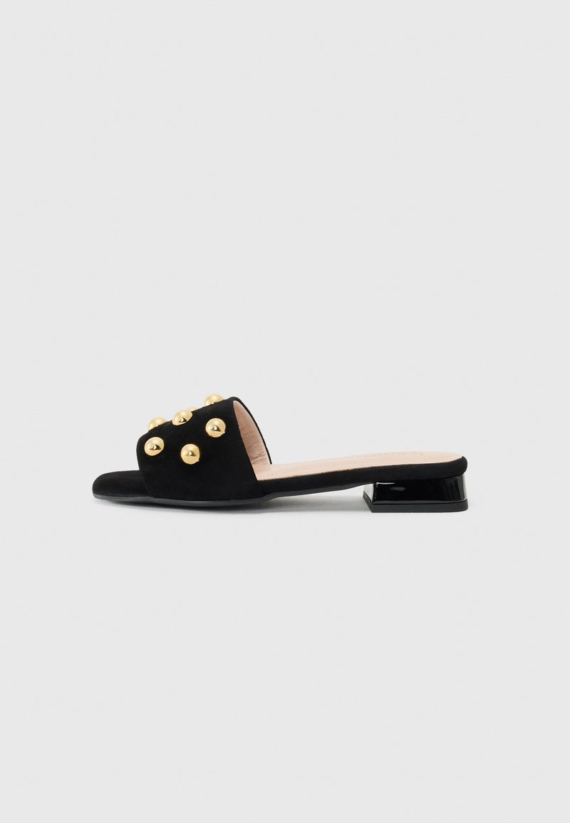 Black suede slip-on shoe with a low block heel, adorned with gold-colored round studs on the upper side and smooth inner lining.