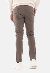 Pantaloni in cotone grigio misto, con vestibilità slim, dotati di due tasche posteriori con chiusura a bottone e orli affusolati, abbinati a sneakers bianche.
