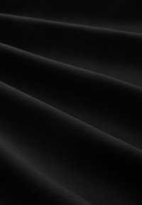 Tessuto nero con una texture liscia, caratterizzato da morbidi drappeggi che creano un senso di profondità e dimensione. La superficie è uniforme e opaca.