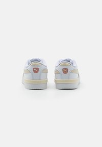 Zapatillas deportivas de cuero blanco con acentos en beige, que cuentan con un diseño texturizado, cuello acolchado y suela de goma. Logo ubicado en el talón.
