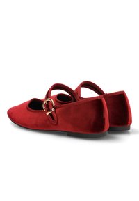 Bailarinas de ante rojo con punta redondeada, tacón plano y tira al tobillo con hebilla dorada. Acabado texturizado, diseño minimalista.
