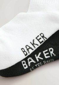 Hvide og sorte sokker med "BAKER" i kontrasttekst. Den hvide sok er struktureret, mens den sorte sok har en glat finish.