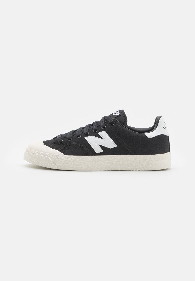 Valkoinen ja musta New Balance -lenkkari, jossa on kanvaalikotelo, valkoinen kumipohja ja valkoinen "N"-logo sivulla, nähtynä ulkosivulta.