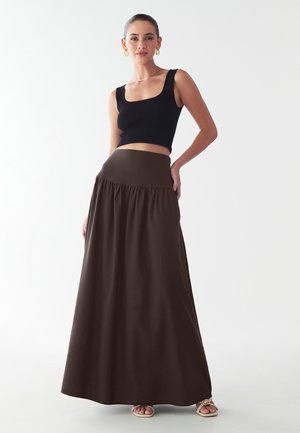 Maxi sukňa z tmavohnedej tkaniny, s vysokým pásom a riasenými detailmi, v kombinácii s čiernym rebrovaným crop topom so štvorcovým výstrihom.