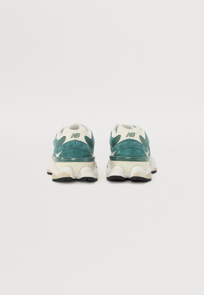 Grüne und cremefarbene New Balance Sneakers mit einem strukturierten Wildleder-Obermaterial, einer auffälligen wellenförmigen Sohle und einem markanten Logo an der Ferse.