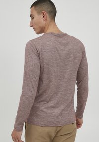 Langærmet skjorte i heathered mauve stof, med rund halsudskæring og tætsiddende design. Glat tekstur uden synlige mønstre eller accenter.