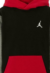 Sudadera con capucha que presenta un cuerpo negro, capucha roja, mangas grises y un bolsillo tipo canguro. Incluye un logo Jumpman blanco en el pecho.