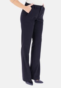Pantaloni blu navy con un motivo a puntini testurizzati, design a gamba dritta, tasche laterali e una vita classica. Abbinati a décolleté nere con punta affilata.