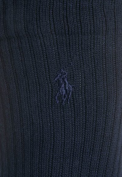 Karatā zila ribota zeķes, izgatavotas no teksturēta auduma, ar mazu dzeltenu izšūtu zirga logotipu tumšākā zila tonī.