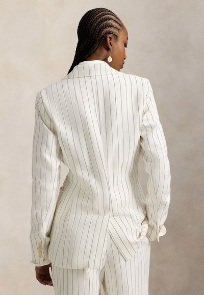 Λευκό σακάκι με ρίγες, κατασκευασμένο από ελαφρύ ύφασμα, με δομημένους ώμους, άνοιγμα στην πλάτη και λεπτομερείς διακοσμητικές κουμπότρυπες.