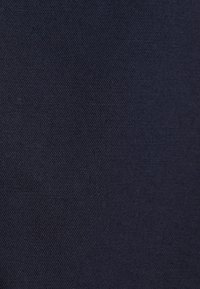 Gros plan sur une texture de tissu bleu foncé avec un motif tissé diagonal fin et une surface lisse.