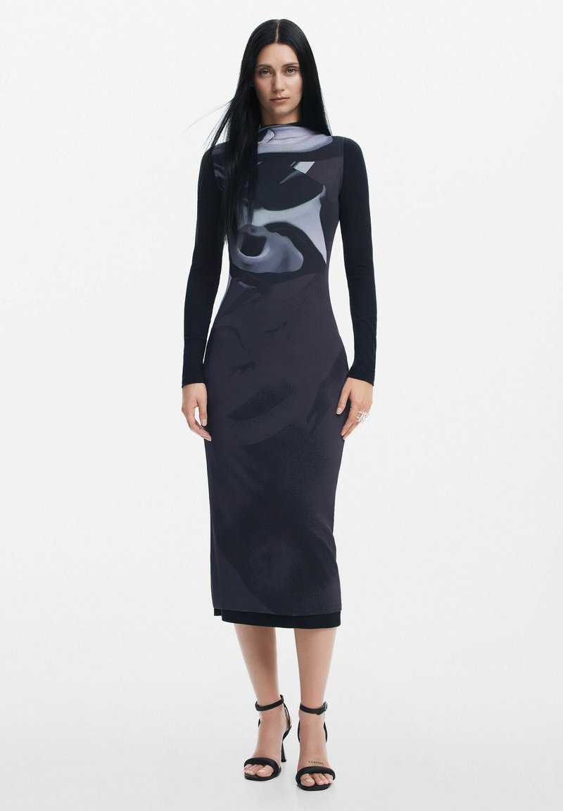 Rochie neagră cu mânecă lungă, având un model abstract gri, siluetă mulată și un despicat pe lateral, completată de tocuri negre cu bretele.