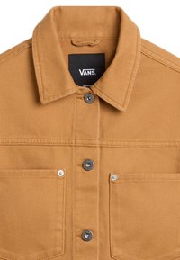 Kurtka dżinsowa w kolorze piaskowym z kołnierzem typu rozłożysty, zapięciem na guziki z przodu, dwoma kieszeniami na piersi z srebrnymi elementami oraz fakturowaną tkaniną.