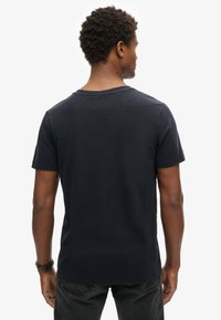 Camiseta azul marino de algodón suave con mangas cortas y cuello redondo, que presenta un corte casual y una textura lisa.
