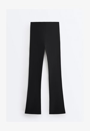 Pantaloni negri cu talie înaltă, ușor evazați la bază, așezați pe o suprafață albă.