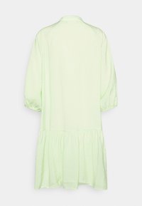 Vestido de algodão verde-claro com decote redondo, mangas bufantes e bainha em camadas, apresentando uma textura suave e uma silhueta descontraída.