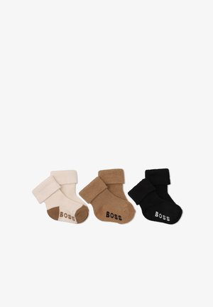 Trois paires de chaussettes bébé pliées en beige, marron et noir, chacune avec "BOSS" écrit sur la zone des orteils.