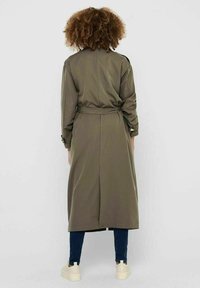 Oliwkowy płaszcz trench z guzikami, z wiązaniem w talii, długimi rękawami i długości midi. Gładki materiał i detal z tyłu w postaci rozcięcia.