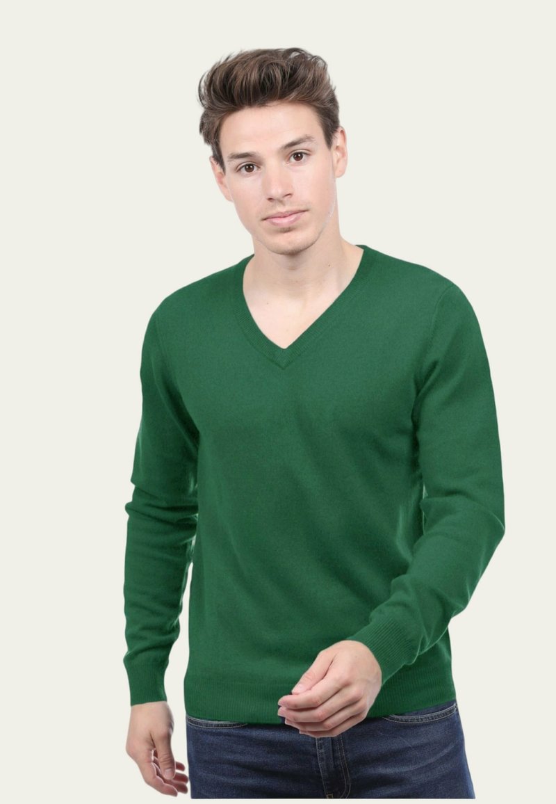 Pull vert en V en tissu doux, avec des manches longues et des poignets côtelés, porté sur un jean bleu. Design simple et classique.