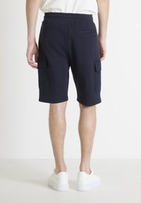 Bermudas cargo azul marino de tela suave, con dos bolsillos laterales y un bolsillo trasero, acabadas con un corte relajado y bordes rematados.