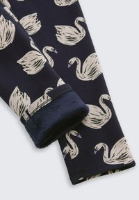 Navy stof met een zwaanpatroon, met een zachte, pluizige manchette. De manchette heeft een donkerblauwe rand die de textuur en het ontwerp accentueert.