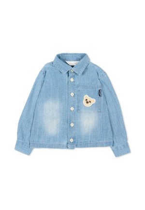 Chemise en denim bleu clair à boutons, manches longues, avec une poche poitrine ornée d'un petit écusson en forme de tête d'ours beige.