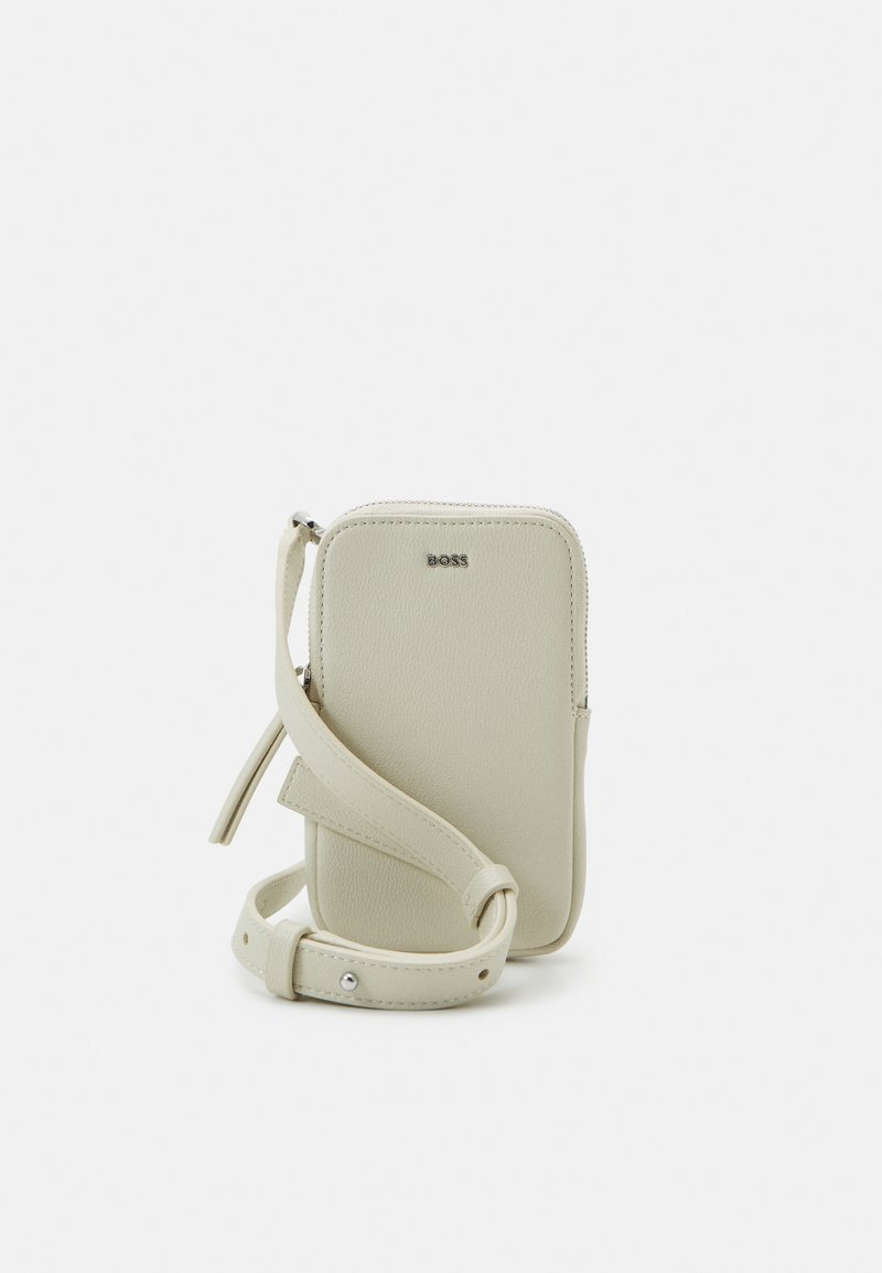 Světle béžová kožená crossbody taška na telefon s uzávěrem na zip, embosovaným logem, nastavitelným popruhem a hladkým povrchem.