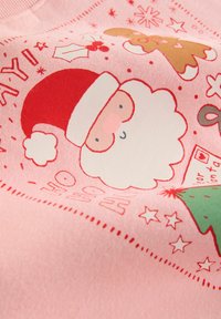 Roze sweatshirt met een Santa Claus afbeelding met een rode hoed, witte baard en een roze neus, samen met motieven van gingerbread en een kerstboom.