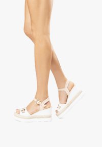 Sandali platform bianchi con accenti beige, cinturino regolabile con fibbia, design open toe e suola in stile espadrilles texturizzata.