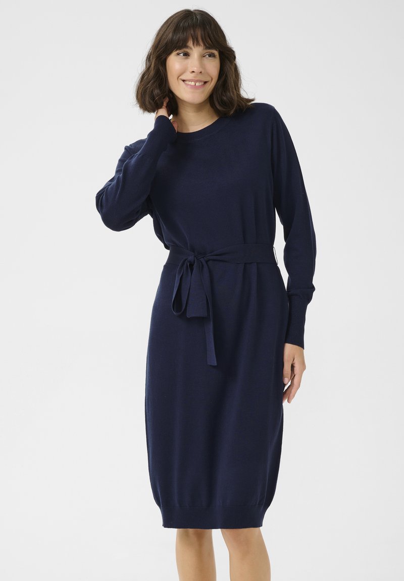 Marineblaues Strickkleid mit langen Ärmeln, einem taillierten Gürtel und einem gerippten Saum. Glatte Textur, knielanges Design und lockerer Schnitt.