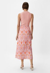 Maxikleid mit einem gerippten rosa Oberteil, fließendem gemustertem Rock in den Farben Rosa, Orange und Lila, mit glatter Oberfläche und einfachem Gürtel.