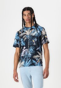 Kortsleeve, marineblå bomullst-skjorte med tropisk blad- og fuglemønster i lys blå og dempede farger. Avslappet passform med rund hals.
