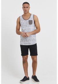 Hallidest ja valgetest mustritest t-särk halli taskuga, koos musta teksapükste ja mustade tossudega. Lihtne, vabaaja stiil.