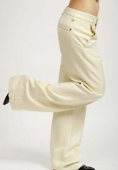 Pantalones de pierna ancha crema con plisados, bolsillos laterales y una textura suave. Terminado con una cinturilla y un ligero brillo.