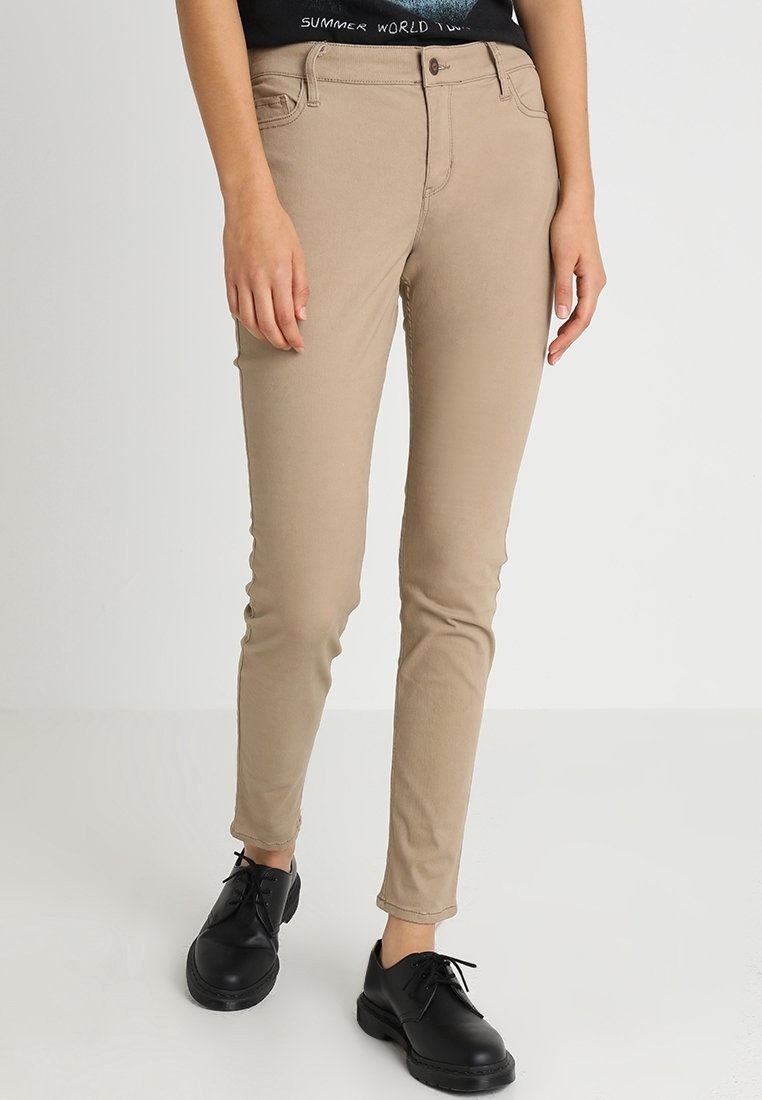 Beige smala jeans med fem fickor, bälteshällor och kontrasterande sömmar, i kombination med svarta snörskor. Slät tyg, slim fit.