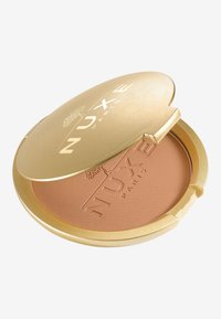 Goldener Kompaktspiegel mit glatter Oberfläche und eingeprägtem Branding. Innen befindet sich ein weicher, matter Bronzer in einer hellbraunen Nuance. Der Kompakt ist halbrund.