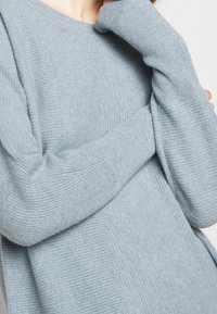 Jasnoniebieski, oversize sweter wykonany z miękkiej, prążkowanej dzianiny, z długimi rękawami i okrągłym dekoltem, o luźnym fasonie.