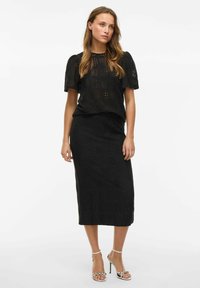 Conjunto de dos piezas de ganchillo negro que incluye una blusa de manga corta con mangas abullonadas y una falda lápiz larga, ambos con patrones intrincados.